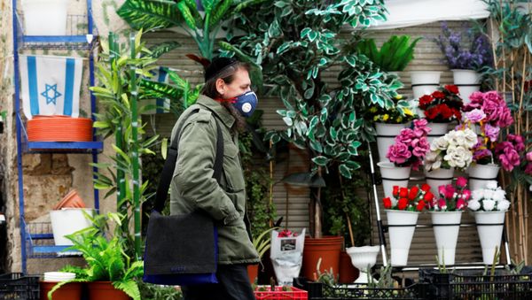 A man wears a face mask as he walks in a market in Ashkelon while Israel tightened a national stay-at-home policy following the spread of coronavirus disease (COVID-19) in Ashkelon, Israel March 20, 2020 - Sputnik International