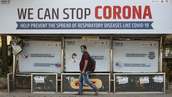 FILE PHOTO: A man wearing a protective mask walks past a bus stop displaying preventive measures against the coronavirus in Mumbai, India, March 18, 2020.  - Sputnik International