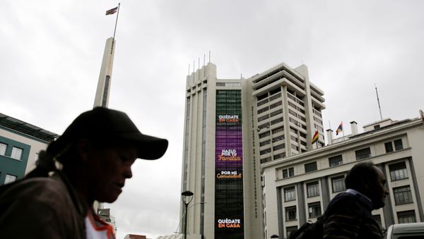 People walk past an electronic sign on the Bolivia's government building displaying the message Stay at home, do it for your family and For my community, as the coronavirus disease (COVID-19) outbreak continues, in downtown La Paz, Bolivia March 20, 2020 - Sputnik International