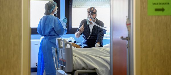 A medical worker wearing a protective mask and suit speaks with a patient suffering from coronavirus disease (COVID-19) in an intensive care unit at the Oglio Po hospital in Cremona, Italy, 19 March 2020.  - Sputnik International