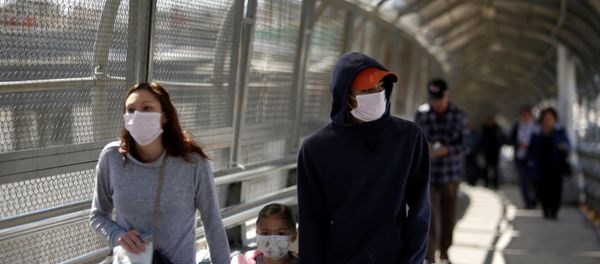 A family wearing protective face masks walks towards the U.S. at the Paso del Norte International Border bridge after the United States and Mexico have agreed to restrict non-essential travel over their shared border in an effort to limit the spread of the new coronavirus (COVID-19), in Ciudad Juarez, Mexico March 20, 2020. - Sputnik International