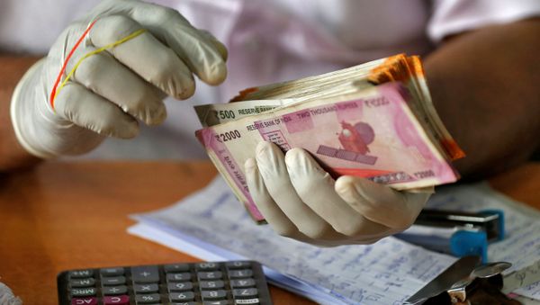 A trader wearing protective hand gloves counts Indian currency notes at a market during a 21-day nationwide lockdown to limit the spreading of coronavirus disease (COVID-19), in Kochi, India, March 27, 2020.  - Sputnik International