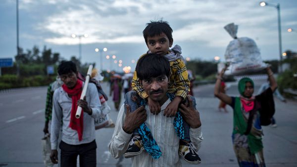 A migrant worker carries his son as they walk along a road with others to return to their village, during a 21-day nationwide lockdown to limit the spreading of coronavirus - Sputnik International