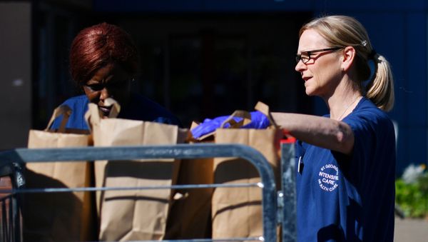 Nurses and staff carry food delivered by volunteers outside St George’s Hospital in London - Sputnik International