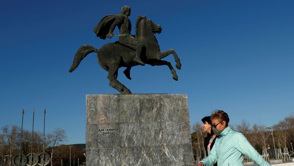 A woman covering her face with a scarf walks past by the statue of Alexander the Great in Thessaloniki, Greece, March 17, 2020. - Sputnik International