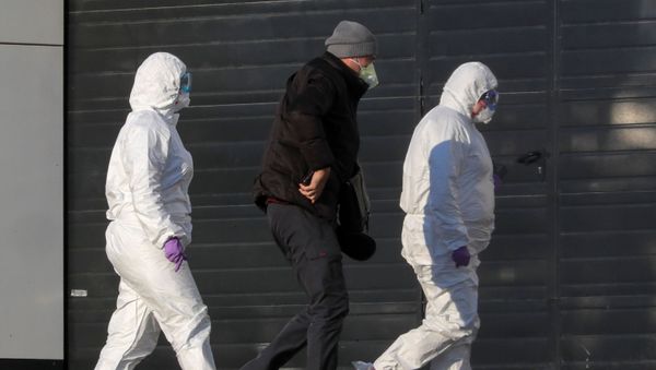 Medical staff members wearing protective suits accompany a man at a hospital, where coronavirus disease (COVID-19) patients are being treated, in Moscow, Russia March 17, 2020 - Sputnik International