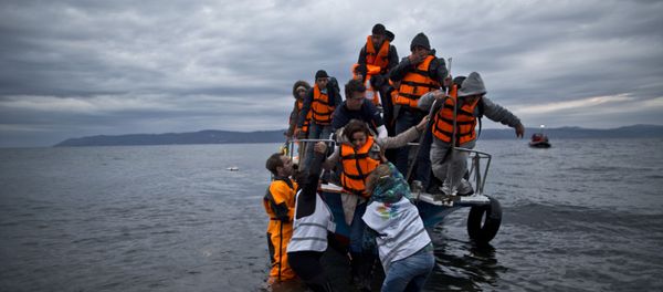 In this Thursday, Dec. 3, 2015 photo, volunteers help refugees disembark from a vessel carrying Yazidi refugee Samir Qasu, 45, from Sinjar, Iraq, and his wife Bessi, 42, their two daughters Delphine, 18, seen center left, Dunia 13, and their two sons Dilshad, 17, seen center left, and Dildar, 10, as it arrives to the northeastern Greek island of Lesbos from the Turkish coast. In this Thursday, Dec. 3, 2015 photo, volunteers help refugees disembark from a vessel carrying Yazidi refugee Samir Qasu, 45, from Sinjar, Iraq, and his wife Bessi, 42, their two daughters Delphine, 18, seen center left, Dunia 13, and their two sons Dilshad, 17, seen center left, and Dildar, 10, as it arrives to the northeastern Greek island of Lesbos from the Turkish coast. - Sputnik International
