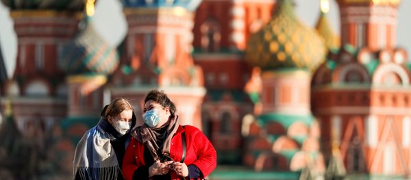 Women with protective masks, widely used as a preventive measure against coronavirus disease (COVID-19), walk across Red Square near the St. Basil's Cathedral in central Moscow, Russia March 26, 2020 - Sputnik International