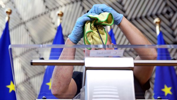 A man disinfects a desk before a news conference of European Council President Charles Michel after after EU heads of state held a videoconference to discuss measures for the coronavirus disease (COVID-19) in Brussels, Belgium, March 26, 2020.  - Sputnik International