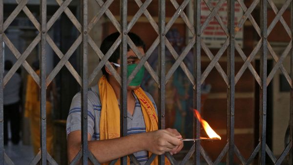 A Hindu priest performs a ritual known as Aarti to bless the devotees (not pictured) on the occasion of Ramnavmi festival at a temple during a 21-day nationwide lockdown to slow the spreading of coronavirus disease (COVID-19) in in Mumbai, India, April 2, 2020. - Sputnik International