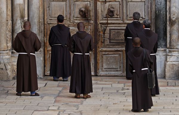 Franciscan monks pray in front of the closed door of the Church of the Holy Sepulchre, in the Christian quarter of the Old City of Jerusalem on March 27, 2020, during the novel coronavirus crisis against which Israel took strict measures Franciscan monks pray in front of the closed door of the Church of the Holy Sepulchre, in the Christian quarter of the Old City of Jerusalem on March 27, 2020, during the novel coronavirus crisis against which Israel took strict measures - Sputnik International