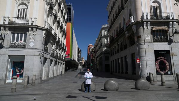 A pharmacist in protective gear stands in a deserted Puerta del Sol square A pharmacist in protective gear stands in a deserted Puerta del Sol square - Sputnik International