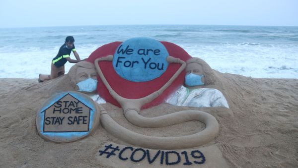 Indian artist Sudarsan Pattnaik puts some final touches as he makes a sand sculpture depicting doctors wearing protective facemasks with a message reading We are For You, Stay Home Stay Safe at Puri beach in Puri on April 3, 2020. Indian artist Sudarsan Pattnaik puts some final touches as he makes a sand sculpture depicting doctors wearing protective facemasks with a message reading We are For You, Stay Home Stay Safe at Puri beach in Puri on April 3, 2020. - Sputnik International