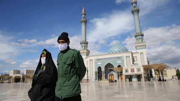 A couple wearing protective face masks, following the outbreak of coronavirus disease (COVID-19), walks on the street in Qom, Iran March 24, 2020. Picture taken March 24, 2020.  - Sputnik International