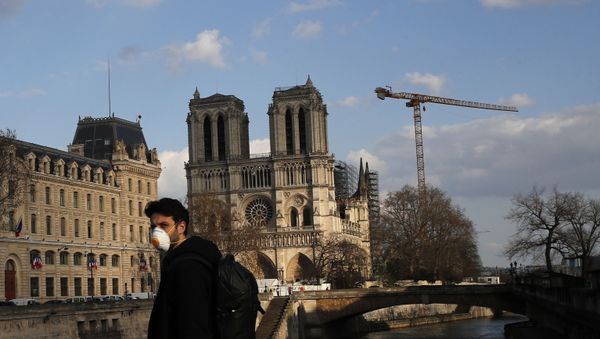 A masked man walks next to Notre Dame Cathedral, in Paris, Wednesday, March 18, 2020. - Sputnik International