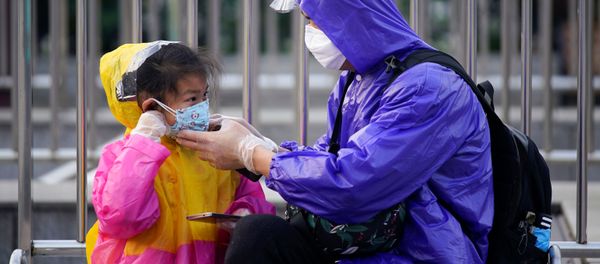 A person helps a child put on a protective face mask at Wuhan's Hankou Railway Station - Sputnik International