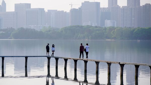 People wearing face masks, walk along the East Lake after lockdown in Wuhan, the epicentre of China's novel coronavirus disease (COVID-19) outbreak, is lifted, in Wuhan, Hubei province, China, April 9, 2020 - Sputnik International