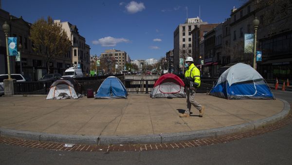 A street maintenance subcontractor for the District of Columbia walks past tents set up by the homeless on a sidewalk in Washington's Dupont Circle. - Sputnik International