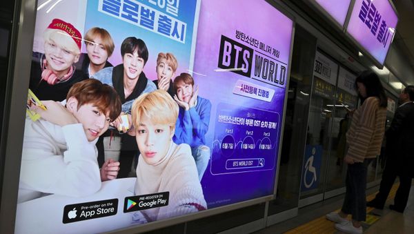 Passengers stand next to an advertisement for the role-playing game BTS World at a subway station in Seoul on June 25, 2019. - Sputnik International