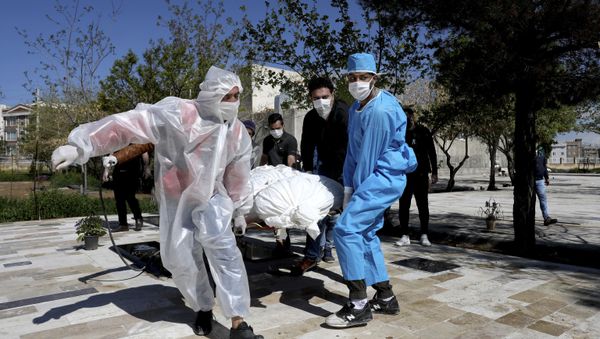 People wearing protective clothing carry the body of a victim who died after being infected with the new coronavirus at a cemetery just outside Tehran, Iran, Monday, March 30, 2020. - Sputnik International