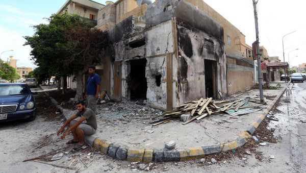 Libyans sit next to a damaged hosue in Sabratha - Sputnik International