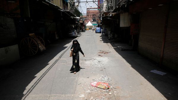 A woman walks on a deserted street during a nationwide lockdown to slow the spreading of the coronavirus disease (COVID-19) in the old quarters of Delhi, India, April 13, 2020 - Sputnik International