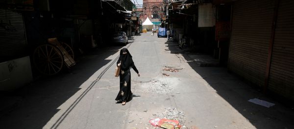 A woman walks on a deserted street during a nationwide lockdown to slow the spreading of the coronavirus disease (COVID-19) in the old quarters of Delhi, India, April 13, 2020 - Sputnik International