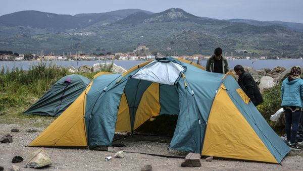 Migrants try to install a tent in the village of Petra on the northeastern Aegean island of Lesbos, Greece, Friday, 27 March 2020. Some 56 migrants who reached Lesbos in smugglers' boats from Turkey over the past few days have been quarantined in small tents in Petra for the past three days. Under public health measures adopted to hinder the spread of the new coronavirus, Greece places all people arriving from abroad in two-week quarantine. Lesbos' main migrant facility, near the village of Moria, is crammed with about 20,000 people even though it was built for 2,700. - Sputnik International