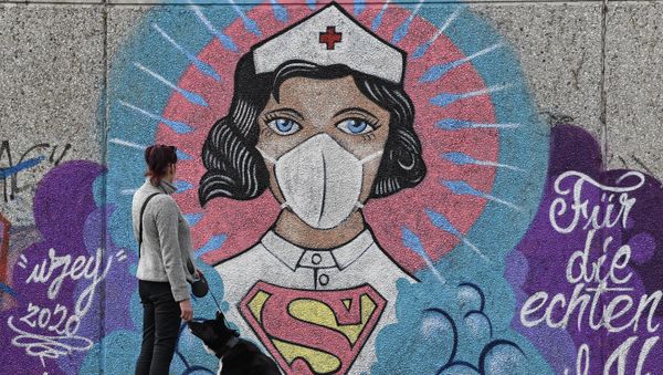 A woman watches a coronavirus graffiti by street artist 'Uzey' showing a nurse as Superwoman on a wall in Hamm, Germany, on Easter Monday, April 13, 2020 A woman watches a coronavirus graffiti by street artist 'Uzey' showing a nurse as Superwoman on a wall in Hamm, Germany, on Easter Monday, April 13, 2020 - Sputnik International