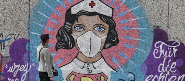 A woman watches a coronavirus graffiti by street artist 'Uzey' showing a nurse as Superwoman on a wall in Hamm, Germany, on Easter Monday, April 13, 2020 - Sputnik International