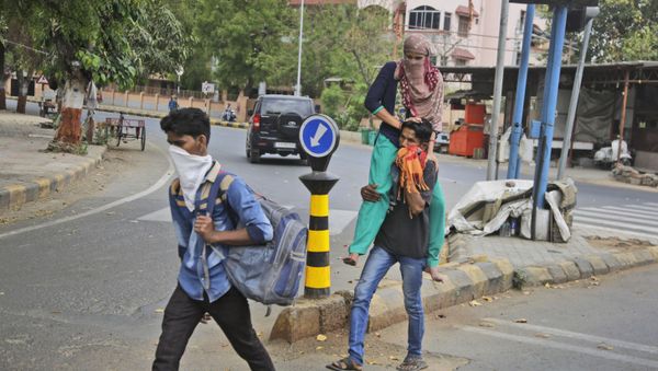 A migrant worker from neighboring state of Rajasthan carries her wife on his shoulder, as they leave for their village after the city comes under lock down as a precautionary measure against COVID-19 in Ahmedabad, India, Thursday, March 26, 2020 A migrant worker from neighboring state of Rajasthan carries her wife on his shoulder, as they leave for their village after the city comes under lock down as a precautionary measure against COVID-19 in Ahmedabad, India, Thursday, March 26, 2020 - Sputnik International