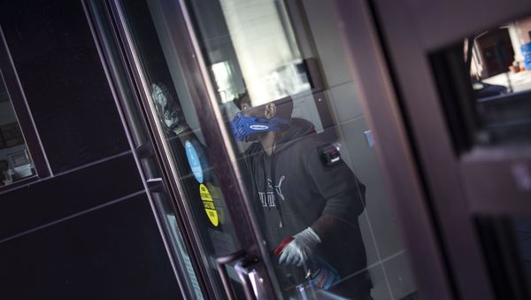 A worker disinfects the front doors of the School Without Walls High School in Washington - Sputnik International