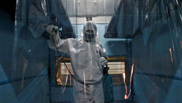 A worker wearing a protective suit disinfects the interior of a passenger train after it was converted into an isolation facility amid concerns about the spread of coronavirus disease (COVID-19), on the outskirts of Kolkata, India, April 6, 2020.  - Sputnik International