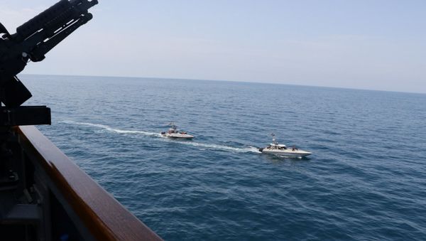 Two Iranian Islamic Revolutionary Guard Corps Navy (IRGCN) vessels, some of several to maneuver in what the U.S. Navy says are unsafe and unprofessional actions against U.S. Military ships by crossing the ships’ bows and sterns at close range is seen next to the guided-missile destroyer USS Paul Hamilton in the Gulf April 15, 2020 - Sputnik International