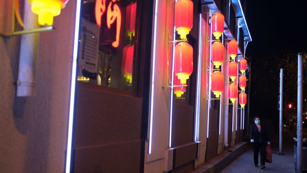 A woman wearing a face mask walks along a street in Beijing, following an outbreak of the novel coronavirus disease (COVID-19), China April 20, 2020.  - Sputnik International