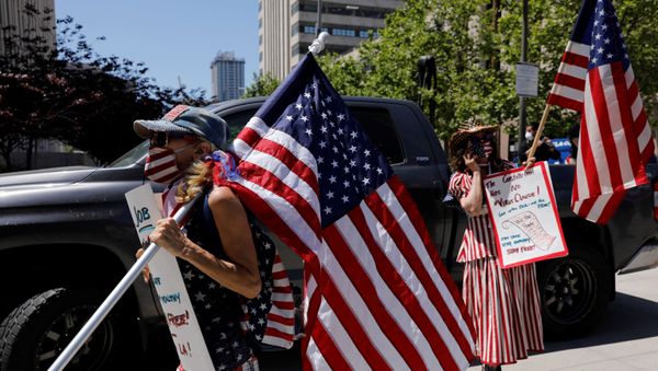 Demonstrators wearing face masks carry placards and U.S. flags as they attend a vehicle caravan protest to call on state and local officials to re-open the economy, during the coronavirus disease (COVID-19) outbreak, near Los Angeles City Hall, Los Angeles, California, U.S., April 22, 2020. - Sputnik International