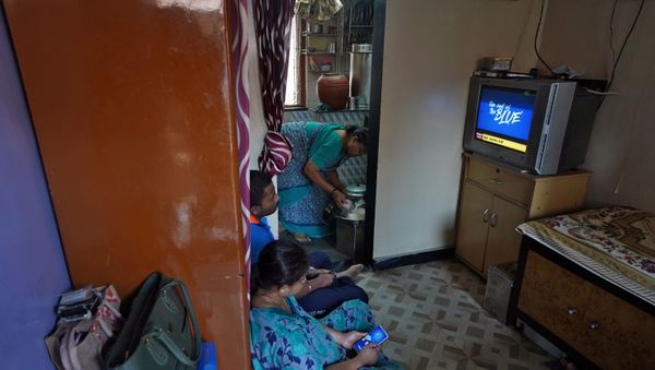 Suvarna Dinesh Rasal, 45, a nurse at Breach Candy Hospital Trust watches TV with her son Atharva Dinesh Rasal, 21, who works at a coffee shop, as Aparna Arvind Lanjekar, 68, mother of Suvarna prepares food as they stay indoors inside their single room apartment at a Chawl, home to hundreds of families, during a 21-day nationwide lockdown to slow the spreading of Coronavirus disease (COVID-19), in Mumbai, India March 31, 2020. - Sputnik International