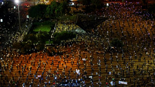 Israelis hold up their mobile phones as they demonstrate against Israel's Prime Minister Benjamin Netanyahu, under strict restrictions made to slow down the coronavirus disease (COVID-19) spread, on Rabin Square in Tel Aviv, Israel 19 April 2020 Israelis hold up their mobile phones as they demonstrate against Israel's Prime Minister Benjamin Netanyahu, under strict restrictions made to slow down the coronavirus disease (COVID-19) spread, on Rabin Square in Tel Aviv, Israel 19 April 2020 - Sputnik International