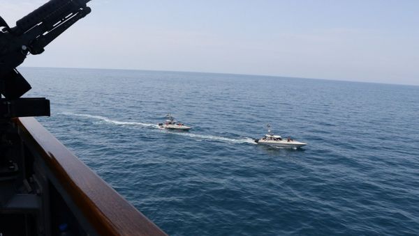 Two Iranian Islamic Revolutionary Guard Corps Navy (IRGCN) vessels, some of several to maneuver in what the U.S. Navy says are unsafe and unprofessional actions against U.S. Military ships by crossing the ships’ bows and sterns at close range is seen next to the guided-missile destroyer USS Paul Hamilton in the Gulf April 15, 2020. U.S. Navy/Handout via REUTERS. - Sputnik International