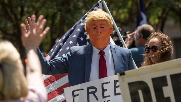 An attendee with a mask dressed to impersonate President Donald Trump walks through the crowd and waves at supporters as a group called Open Texas rally to re-open Texas businesses, places of work and religious services shut down by coronavirus (COVID-19) pandemic restrictions as they gather in a park outside of the City Hall in Frisco, Texas, U.S., April 25, 2020.  - Sputnik International