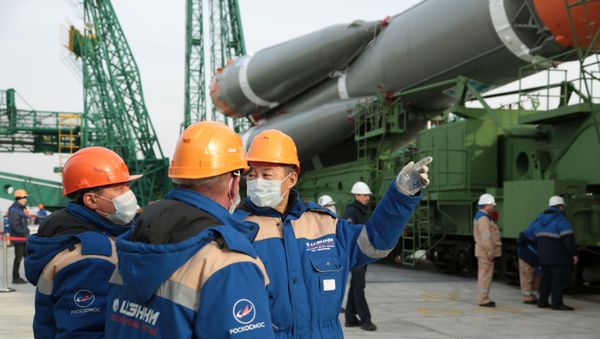 Specialists wearing protective face masks talk near the Soyuz MS-16 spacecraft for the next International Space Station (ISS) crew formed of Chris Cassidy of NASA, Anatoly Ivanishin and Ivan Vagner of the Russian space agency Roscosmos, which is prepared to be set at the launchpad ahead of its upcoming launch at the Baikonur Cosmodrome, Kazakhstan April 6, 2020. - Sputnik International