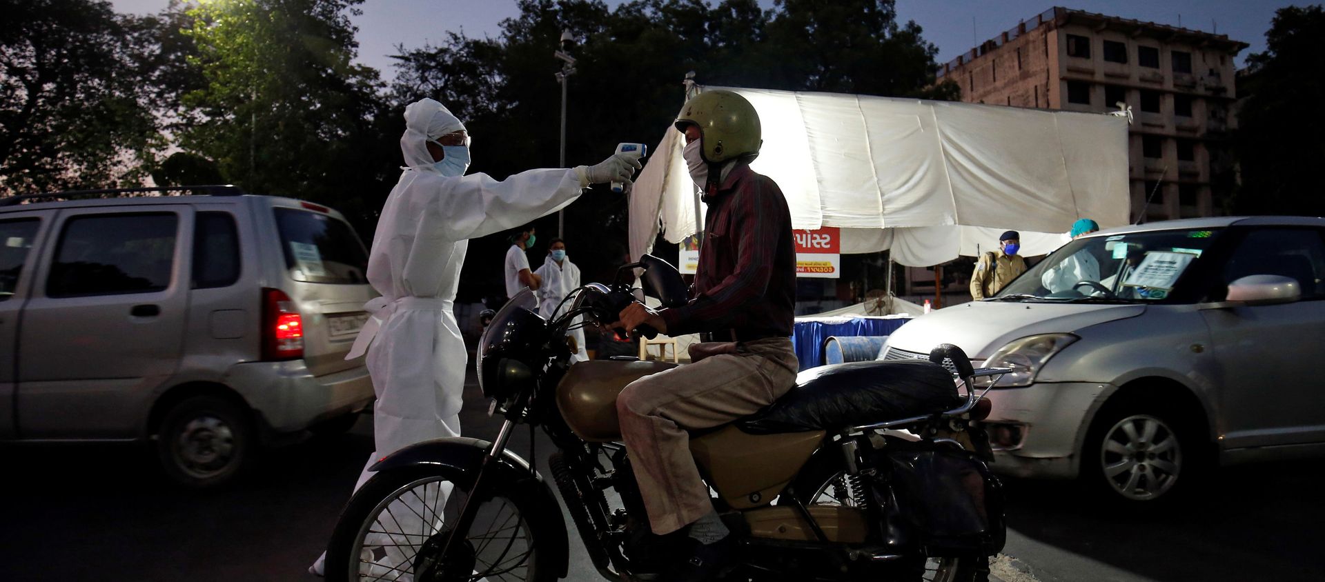 A health worker uses an infrared thermometer to measure the temperature of a motorcyclist on a road in India - Sputnik International, 1920, 28.04.2020