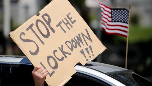 A demonstrator holds a placard during a vehicle caravan protest to call on state and local officials to re-open the economy, during the coronavirus disease (COVID-19) outbreak, near Los Angeles City Hall, Los Angeles, California, U.S., April 22, 2020 - Sputnik International