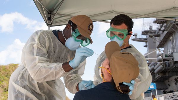 U.S. Navy Hospitalmen Christian Akins, left, from Atlanta, Ga., and Austin Brunt, from Charleston, S.C., assigned to Naval Hospital Guam, take a nasal sample from a U.S. Sailor assigned to the aircraft carrier USS Theodore Roosevelt (CVN 71) as part of a public health outbreak investigation April 23, 2020 U.S. Navy Hospitalmen Christian Akins, left, from Atlanta, Ga., and Austin Brunt, from Charleston, S.C., assigned to Naval Hospital Guam, take a nasal sample from a U.S. Sailor assigned to the aircraft carrier USS Theodore Roosevelt (CVN 71) as part of a public health outbreak investigation April 23, 2020 - Sputnik International