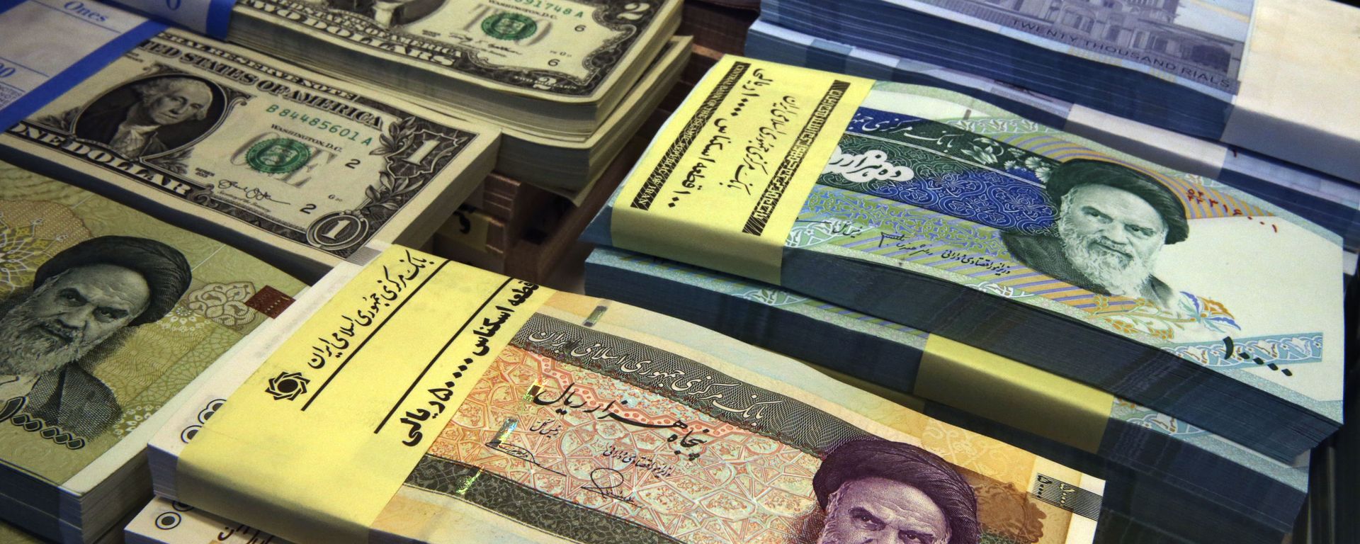 In this 4 April 2015 file photo, Iranian and U.S. banknotes are on display at a currency exchange shop in downtown Tehran, Iran. Iran's president has sent a bill to Parliament that would cut four zeroes from the value of the nation's sanctions-battered currency, the rial. Semi-official news agencies reported the news on Wednesday, 21 August 2019, saying President Hassan Rouhani sent the bill with urgency to the Parliament to consider. Iran's rial has been hammered by the effects of increasing US sanctions on the country. In this 4 April 2015 file photo, Iranian and U.S. banknotes are on display at a currency exchange shop in downtown Tehran, Iran. Iran's president has sent a bill to Parliament that would cut four zeroes from the value of the nation's sanctions-battered currency, the rial. Semi-official news agencies reported the news on Wednesday, 21 August 2019, saying President Hassan Rouhani sent the bill with urgency to the Parliament to consider. Iran's rial has been hammered by the effects of increasing US sanctions on the country. - Sputnik International, 1920, 13.10.2020