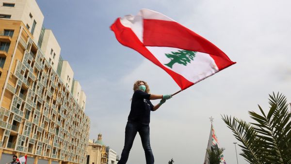 An anti-government demonstrator holds a Lebanese flag as she stands on top of her car, during a countrywide lockdown to combat the spread of the coronavirus disease (COVID-19), in Beirut, Lebanon April 21, 2020.  - Sputnik International