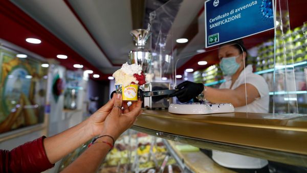 A woman uses tongs to serve ice cream at a cafe, as Italy begins a staged end to a nationwide lockdown due to the spread of the coronavirus disease (COVID-19), in Rome, Italy May 5, 2020 - Sputnik International