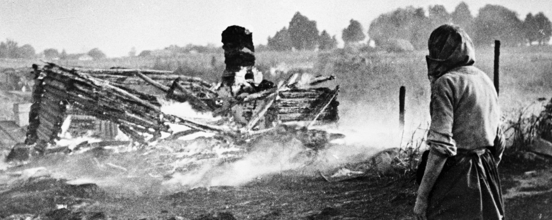 A woman stands next to a burnt house in a village during WW II - Sputnik International, 1920, 16.01.2026