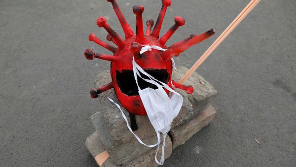 A coronavirus-shaped helmet and protective masks are kept on a stone - Sputnik International