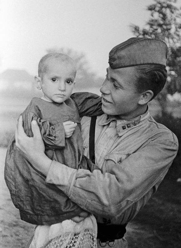 A Soviet officer (right) holds a girl saved from the village of Elkhotovo, 1942 A Soviet officer (right) holds a girl saved from the village of Elkhotovo, 1942 - Sputnik International